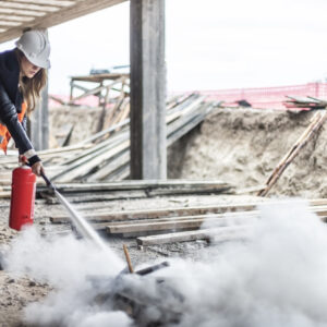 Female rescue worker with a fire extinguisher on construction site