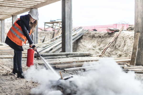 Female rescue worker with a fire extinguisher on construction site